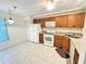 Kitchen featuring tile flooring, wooden cabinets, white appliances, and granite countertops at 200 Lemon Tree Ln # A, Ormond Beach, FL 32174