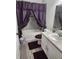 Clean bathroom with white vanity, tub, and purple accents at 309 Burrowing Owl Ln, Winter Haven, FL 33880