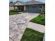 A large, multi-colored paver driveway leads to the garage at 309 Burrowing Owl Ln, Winter Haven, FL 33880