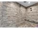 Modern bathroom boasts stylish gray tile shower, pebbled floor, and elegant black marble bench at 506 Parrott Rd, Auburndale, FL 33823