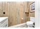 This half bathroom has wood paneled walls, neutral vinyl flooring, and white fixtures at 506 Parrott Rd, Auburndale, FL 33823