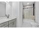 Modern bathroom with white marble-style tile, gray vanity, and enclosed shower with black hardware at 833 Texas Ave, Lakeland, FL 33815