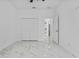 Bright bedroom with white marble floors, closet, and open doorway to a white hallway at 833 Texas Ave, Lakeland, FL 33815