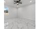 Bright bedroom featuring modern ceiling fan, white walls, and marble-style tile flooring at 833 Texas Ave, Lakeland, FL 33815