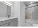 Modern bathroom featuring a gray vanity with marble countertops and a bathtub with glass doors at 835 Texas Ave, Lakeland, FL 33815