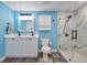 Bright bathroom with double sinks, blue walls, and a modern glass-enclosed shower with marbled tile at 1220 George St, Winter Springs, FL 32708