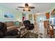 Inviting living room features wood floors, a ceiling fan, comfortable seating, and views into the kitchen and dining area at 38 Seaside Dr, Ormond Beach, FL 32176