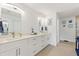 Bathroom with double vanity, white cabinetry, framed mirrors, and tiled shower at 4101 Poinciana Dr, Indian Lake Estates, FL 33855