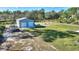 Large metal outbuilding with two roll-up doors, surrounded by a well-maintained lawn and mature trees at 4101 Poinciana Dr, Indian Lake Estates, FL 33855