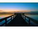 Scenic view of the community pier extending over a tranquil lake at dusk, with a colorful sky at 4101 Poinciana Dr, Indian Lake Estates, FL 33855