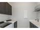 A modern laundry room featuring front loading washer and dryer, upper and lower cabinets, and stainless steel sink at 5243 Sw 88Th Cir, Ocala, FL 34481