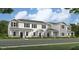 A view of townhomes featuring white siding, green shutters and nicely manicured landscaping at 5896 Meditation Dr, Clermont, FL 34714