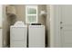 Bright laundry room with white washer, dryer, shelving, window, and neutral colored walls at 946 Hour Glass Rd, Lakeland, FL 33801