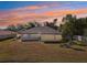 Backyard view with screened-in lanai, simple landscaping, and expansive grassy area at sunset at 562 Dowling Cir, Lady Lake, FL 32159