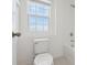 Well-lit bathroom with a white toilet, tiled shower, and a window for natural lighting at 6973 Wilson Pasture Ave, Groveland, FL 34736