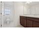 Bright bathroom with dual sinks, granite counters, modern fixtures, and a separate toilet area at 6973 Wilson Pasture Ave, Groveland, FL 34736