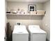 Functional laundry room with white appliances, shelving, and storage containers for organization at 2206 Old Mining Rd, Lakeland, FL 33801