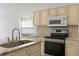 Kitchen with stainless steel appliances, a center island with sink and granite counters and cream cabinets at 131 Vine Dr, Davenport, FL 33837