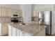 Kitchen with stainless steel appliances, a center island with sink and granite counters and cream cabinets at 131 Vine Dr, Davenport, FL 33837