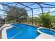 Relaxing screened-in pool area with blue water, spa, surrounding plants, and a comfortable chair at 131 Vine Dr, Davenport, FL 33837