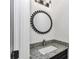 Stylish powder room featuring granite countertop, modern lighting, and decorative round mirror at 7 Hill Prince Dr, Ocala, FL 34482