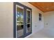 View of the covered patio with tongue and groove ceiling, exterior walls, and double doors at 7 Hill Prince Dr, Ocala, FL 34482