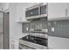 Close-up of the kitchen featuring stainless steel appliances and gray backsplash at 2310 Laguna Dr, Indian Lake Estates, FL 33855