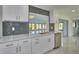 Bright kitchen featuring white cabinets, grey backsplash and stainless steel sink at 2310 Laguna Dr, Indian Lake Estates, FL 33855