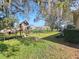 Large backyard with lush lawn, mature trees, playhouse, and swing set at 5685 Lake Victoria Dr, Lakeland, FL 33813