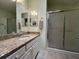 Bathroom with a granite vanity, decorative mirror, white cabinets, and a glass-enclosed shower at 992 Davit Pl, The Villages, FL 32162