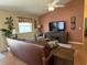 Cozy living room with vaulted ceiling, hardwood floors, a leather sofa, TV, and decorative accents at 992 Davit Pl, The Villages, FL 32162