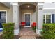 Charming covered entrance with a navy door, small red table, and two red chairs at 12313 Citruswood Dr, Orlando, FL 32832
