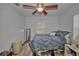 Bedroom features a ceiling fan, light walls, wood floors, and a blue paisley comforter at 10774 Sw 185Th Ter, Dunnellon, FL 34432