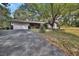 Street view of home with a two-car garage and a stone accent front beneath a mature shade tree at 10774 Sw 185Th Ter, Dunnellon, FL 34432