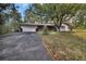 View of the home with a two-car garage and a stone accent front with a mature shade tree at 10774 Sw 185Th Ter, Dunnellon, FL 34432