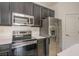 Modern kitchen featuring stainless steel appliances, dark cabinetry, and white countertops at 1006 Breggia Ct, Haines City, FL 33844