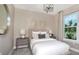 Bright bedroom featuring neutral tones, a plush bed, decorative wall art, and a sunlit window at 1671 Ruby Ln, Lake Alfred, FL 33850