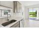 Well-lit kitchen featuring marble counters, a stainless steel sink, and a view of the backyard through a window at 1671 Ruby Ln, Lake Alfred, FL 33850