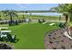 Lawn game area featuring cornhole in backyard near the water, palm trees, lounge chairs and lush landscaping at 288 Woodsage Pl, Lake Alfred, FL 33850