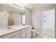 Bright bathroom featuring double sinks, a large mirror, and a tiled shower with neutral color palette at 288 Woodsage Pl, Lake Alfred, FL 33850
