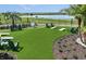 Outdoor lawn games area with cornhole, Adirondack chairs and lush landscaping by a lake at 288 Woodsage Pl, Lake Alfred, FL 33850