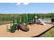 Green and brown playground equipment is built on top of woodchips, with a nearby walking trail at 288 Woodsage Pl, Lake Alfred, FL 33850