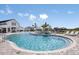 View of the community pool with chairs, tables and an adjacent clubhouse in a community at 288 Woodsage Pl, Lake Alfred, FL 33850