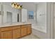 Bright bathroom featuring a double sink vanity, a large mirror, and a soaking tub with tile surround at 3890 Wood Thrush Dr, Kissimmee, FL 34744