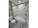 Bright bathroom with marble tile surround, black fixtures and shower rod, and gray wood-look floors at 1260 Buckeye Ne Rd, Winter Haven, FL 33881