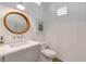 Well-lit half bathroom featuring wainscotting and a round mirror above the sink at 472 Desoto Dr, New Smyrna Beach, FL 32169