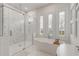 A bright bathroom has a glass enclosed shower and free-standing tub near shuttered windows at 472 Desoto Dr, New Smyrna Beach, FL 32169