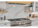 Close-up of a high-end stainless steel range with quartz backsplash and floating wood shelves, blending style and functionality at 472 Desoto Dr, New Smyrna Beach, FL 32169