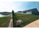 Scenic backyard view featuring lush green grass, a serene pond, and solar panels, combining nature and efficiency at 891 Galloway St, Lake Alfred, FL 33850