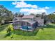 Aerial view of a house with a screened-in pool, surrounded by lush green lawn and mature trees at 17416 Magnolia Island Blvd, Clermont, FL 34711